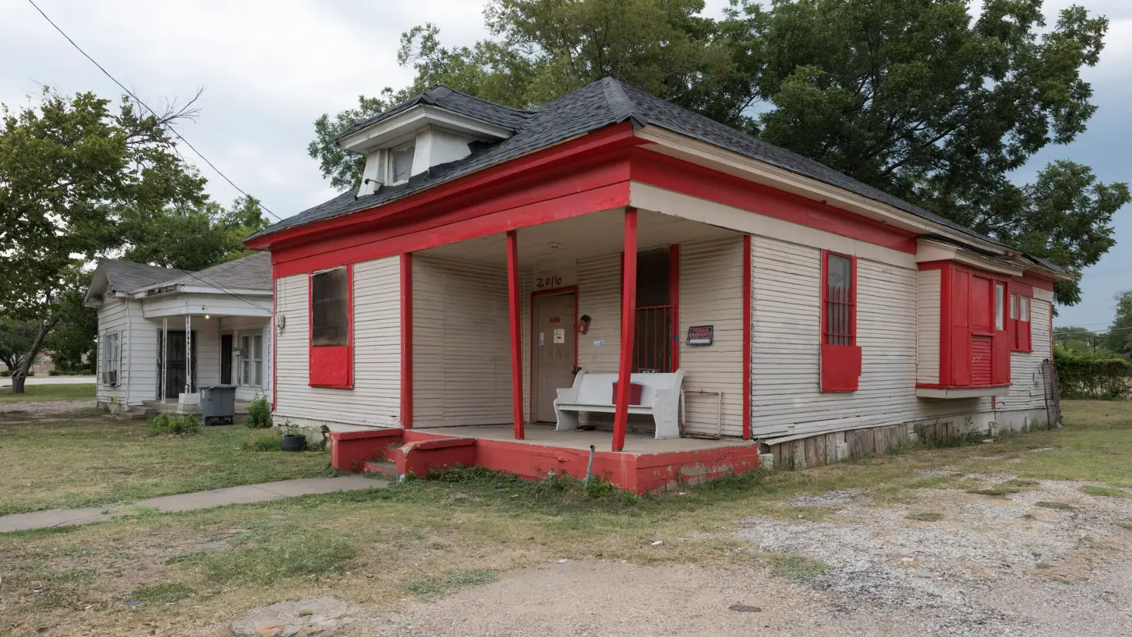 A modest older Texas home with a red front porch